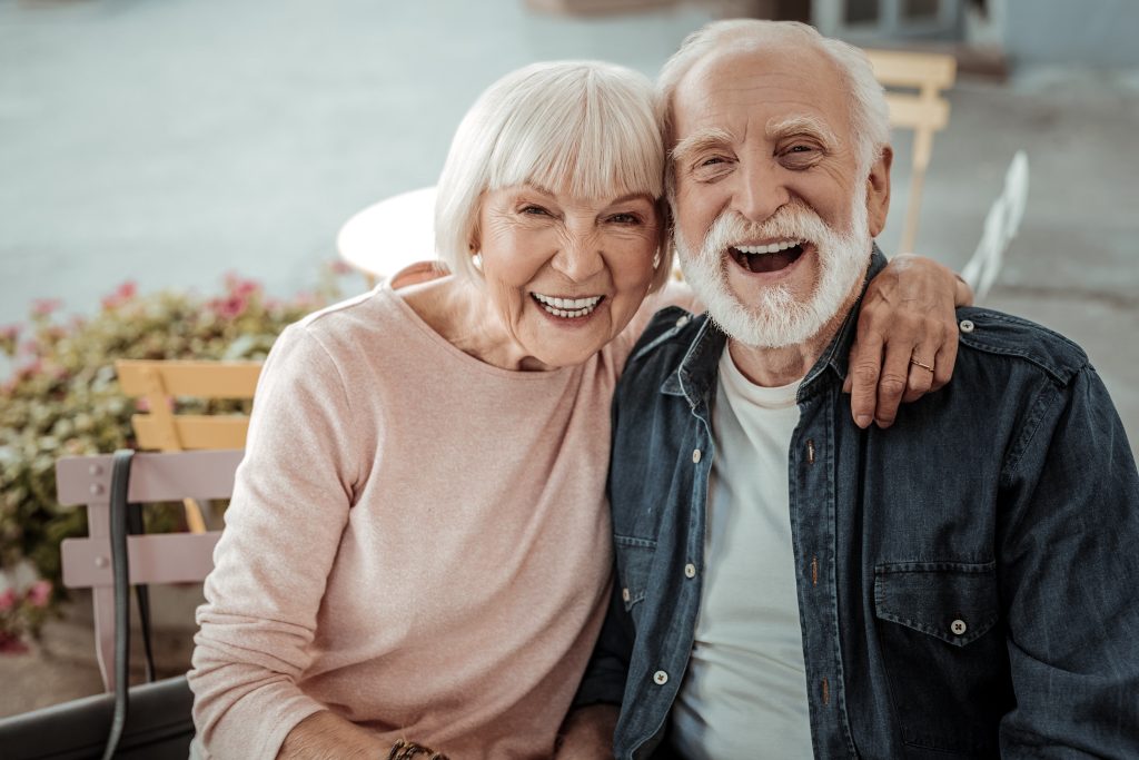 Pareja de adultos mayores sonriendo alegremente mientras se abrazan
